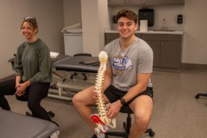 DPT students in class. The student on the right is holding a model of a spine.