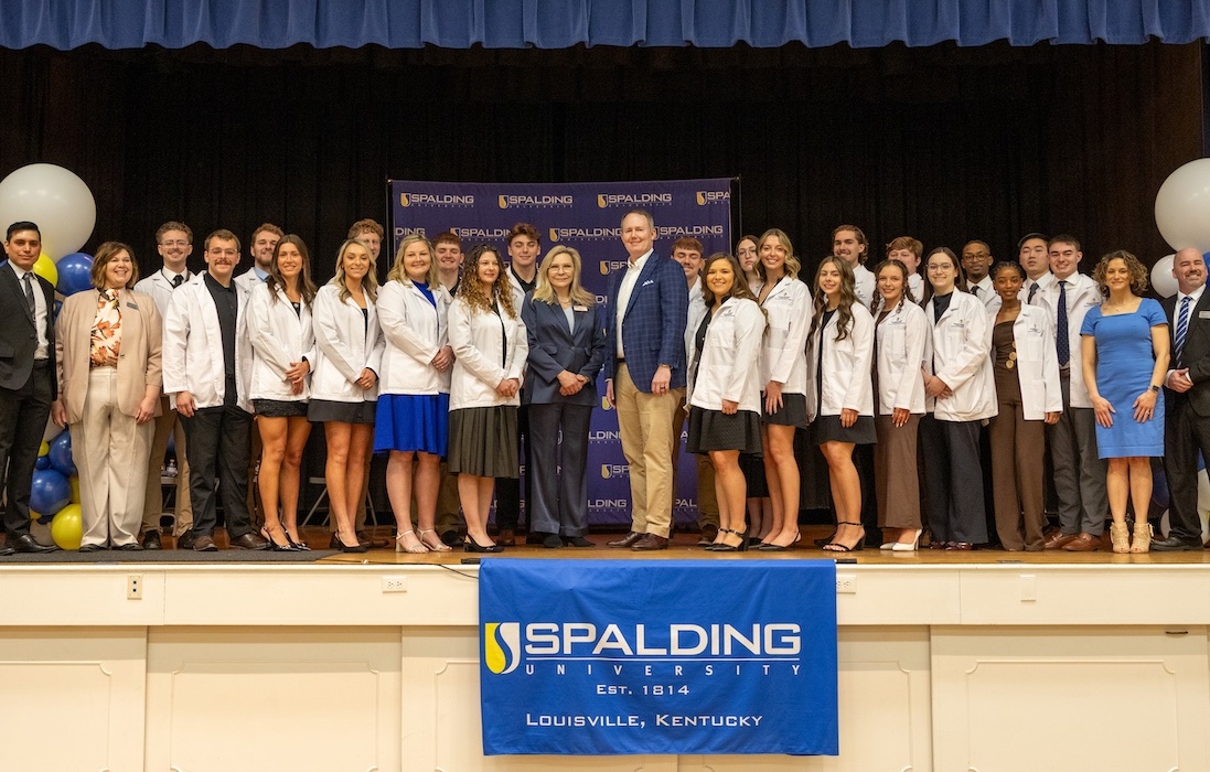 Doctor of Physical Therapy students on stage with President Anne Kenworthy, and DPT faculty.