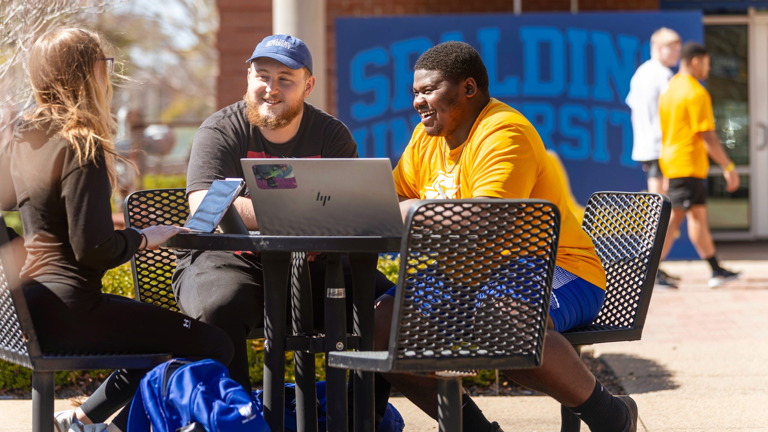 male students sitting at table outside