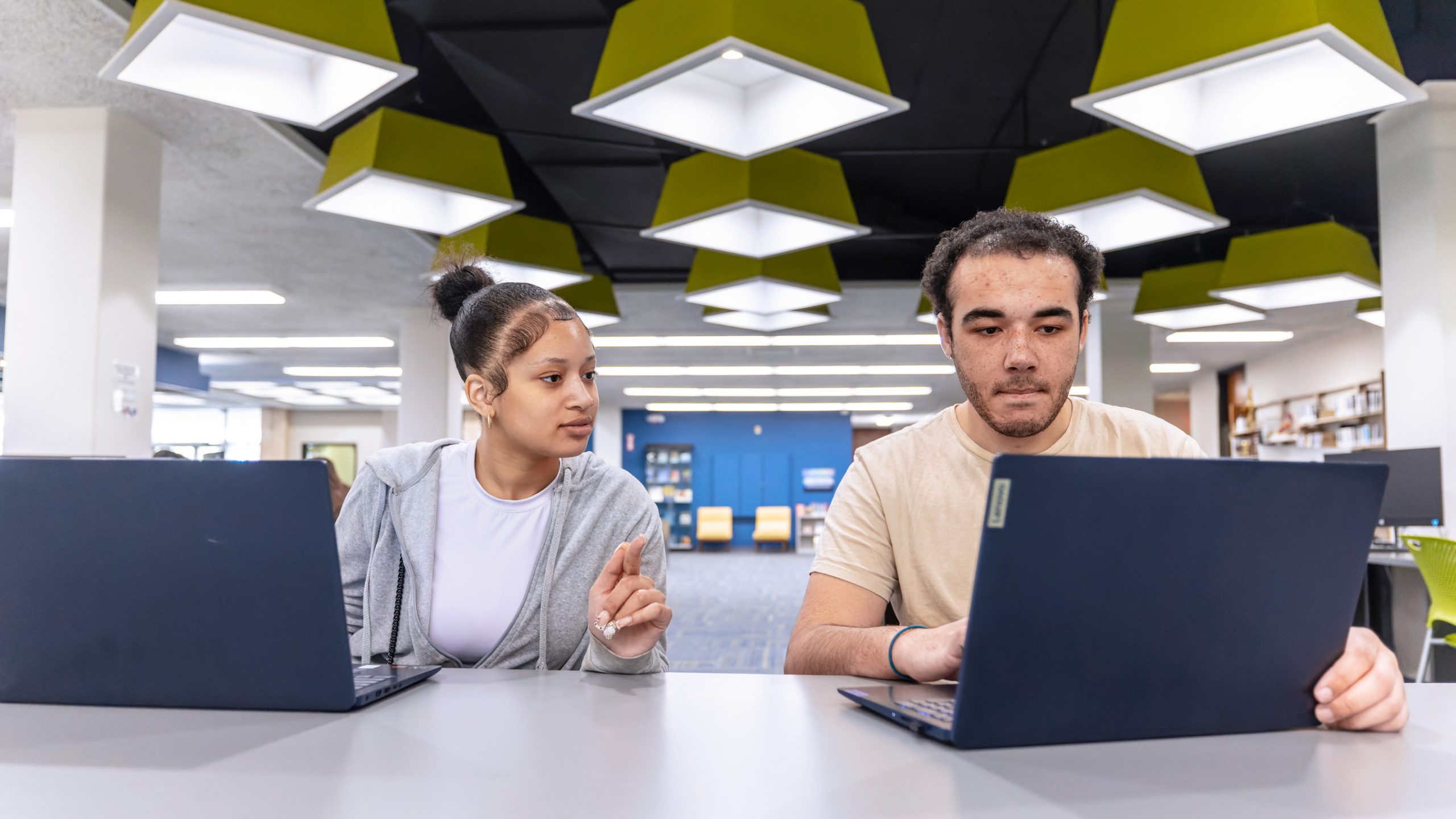 female student sitting next to male student both with laptops