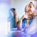 female student in class smiling with hand to chin