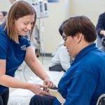 Occupational therapy program student practices moving someone out of a wheelchair