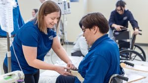 Occupational therapy program student practices moving someone out of a wheelchair