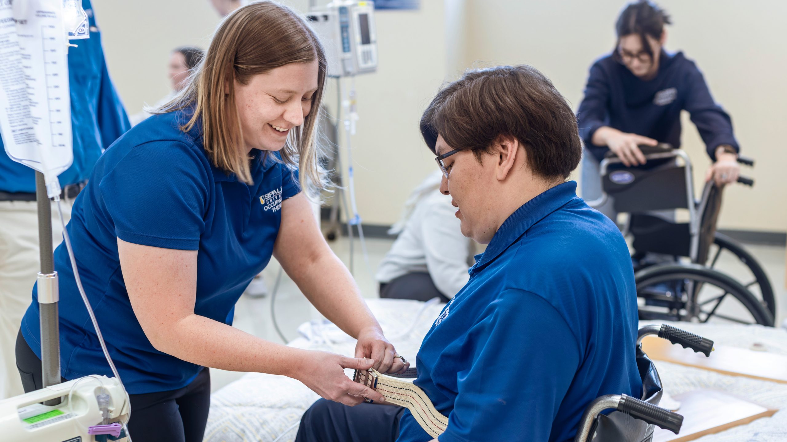 Occupational therapy program student practices moving someone out of a wheelchair