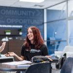 two female students sitting at a table talking and smiling