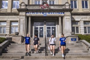 four female students walking down stairs out of university building