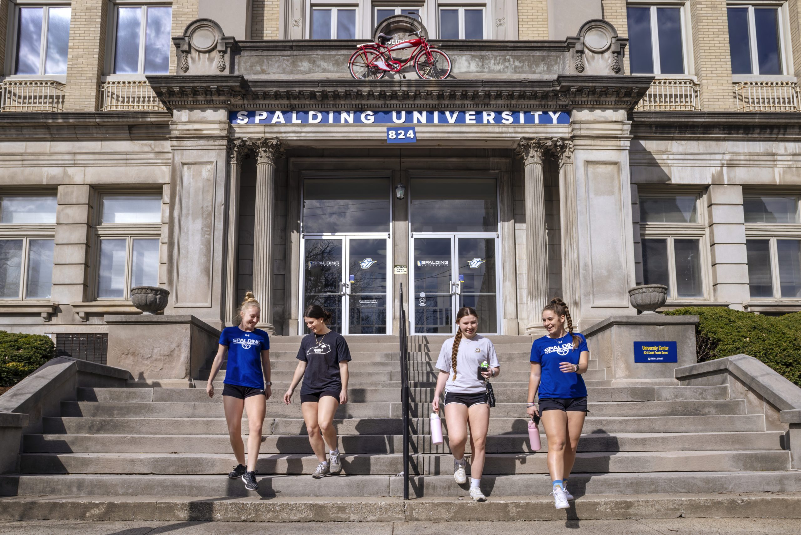 four female students walking down stairs out of university building