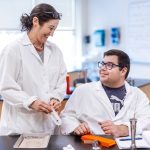 student and teacher in lab coats working in science lab