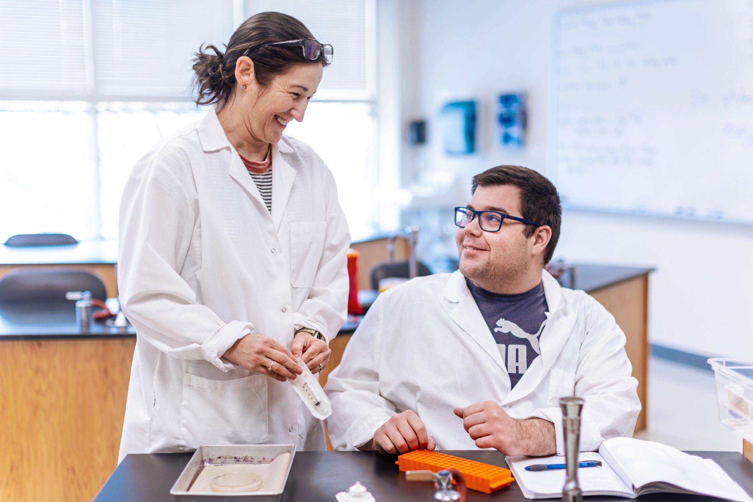 student and teacher in lab coats working in science lab