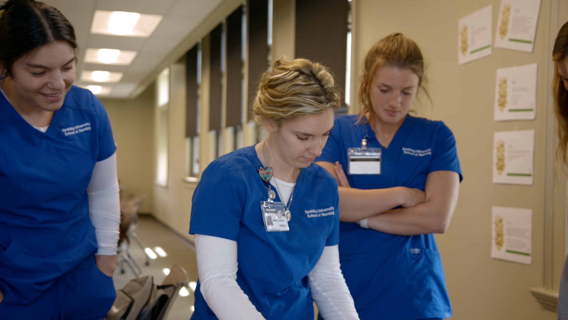 Spalding accelerated nursing students in blue scrubs gather in a hallway