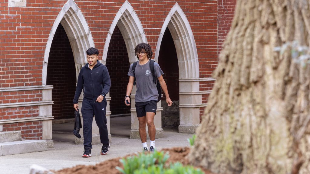 Two students walk outside on a sidewalk on the Spalding campus