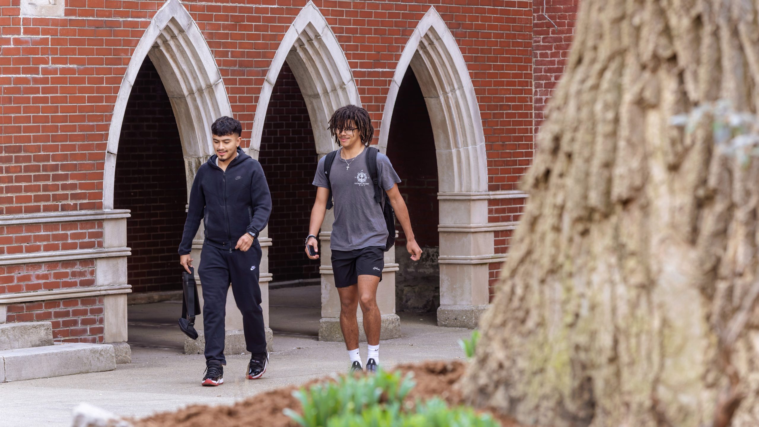 Two students walk outside on a sidewalk on the Spalding campus