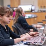 A small group of students work on laptops in a science lab setting