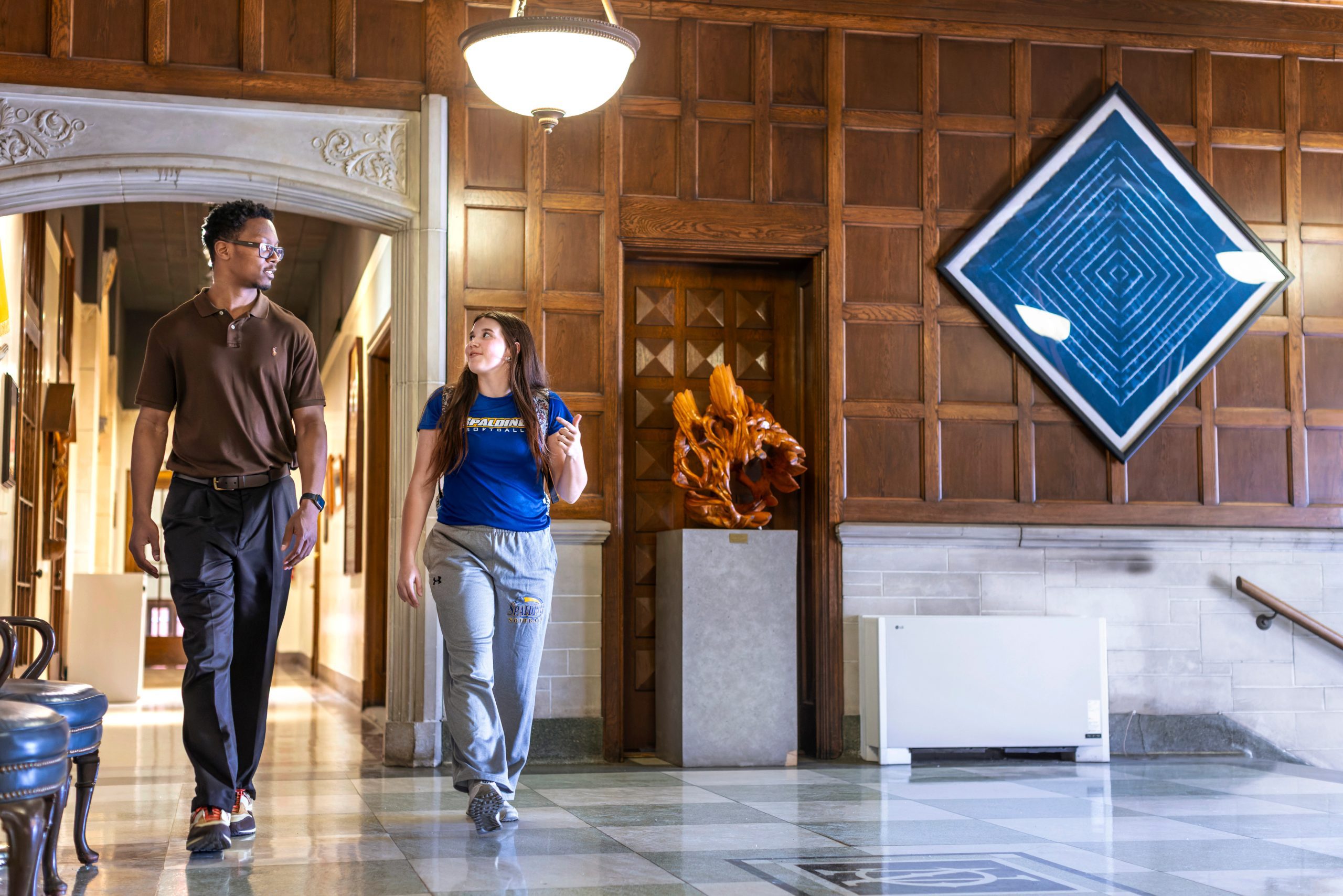 Two students walking inside a lobby of a building at Spalding