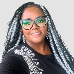 Headshot of a black middle aged woman with long braids and glasses in a black shirt