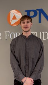 Male college student in a long sleeve gray shirt talks directly to camera