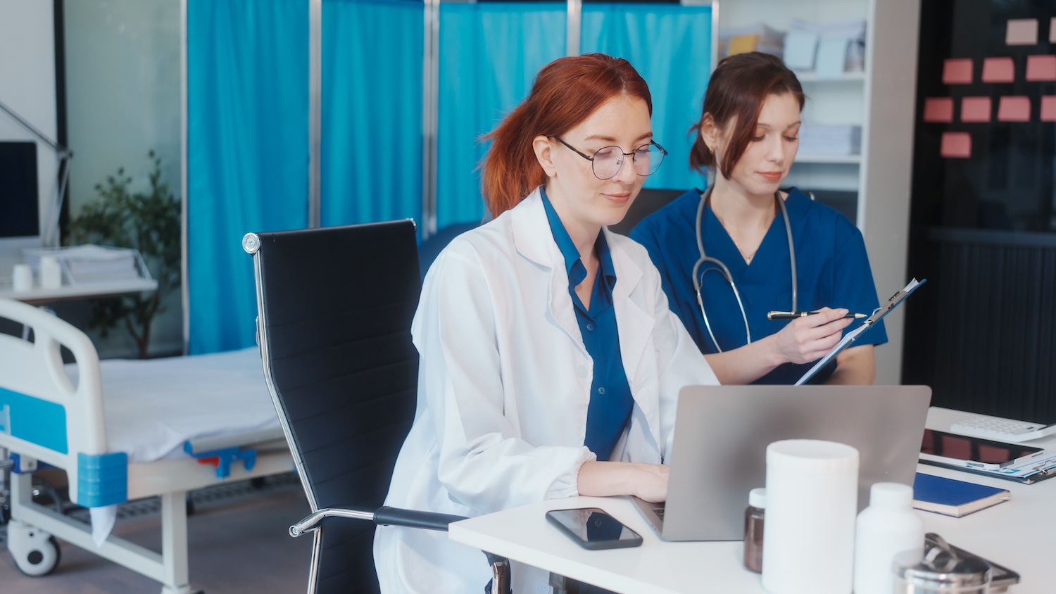 Doctor and medical assistant reviewing patient record at computer